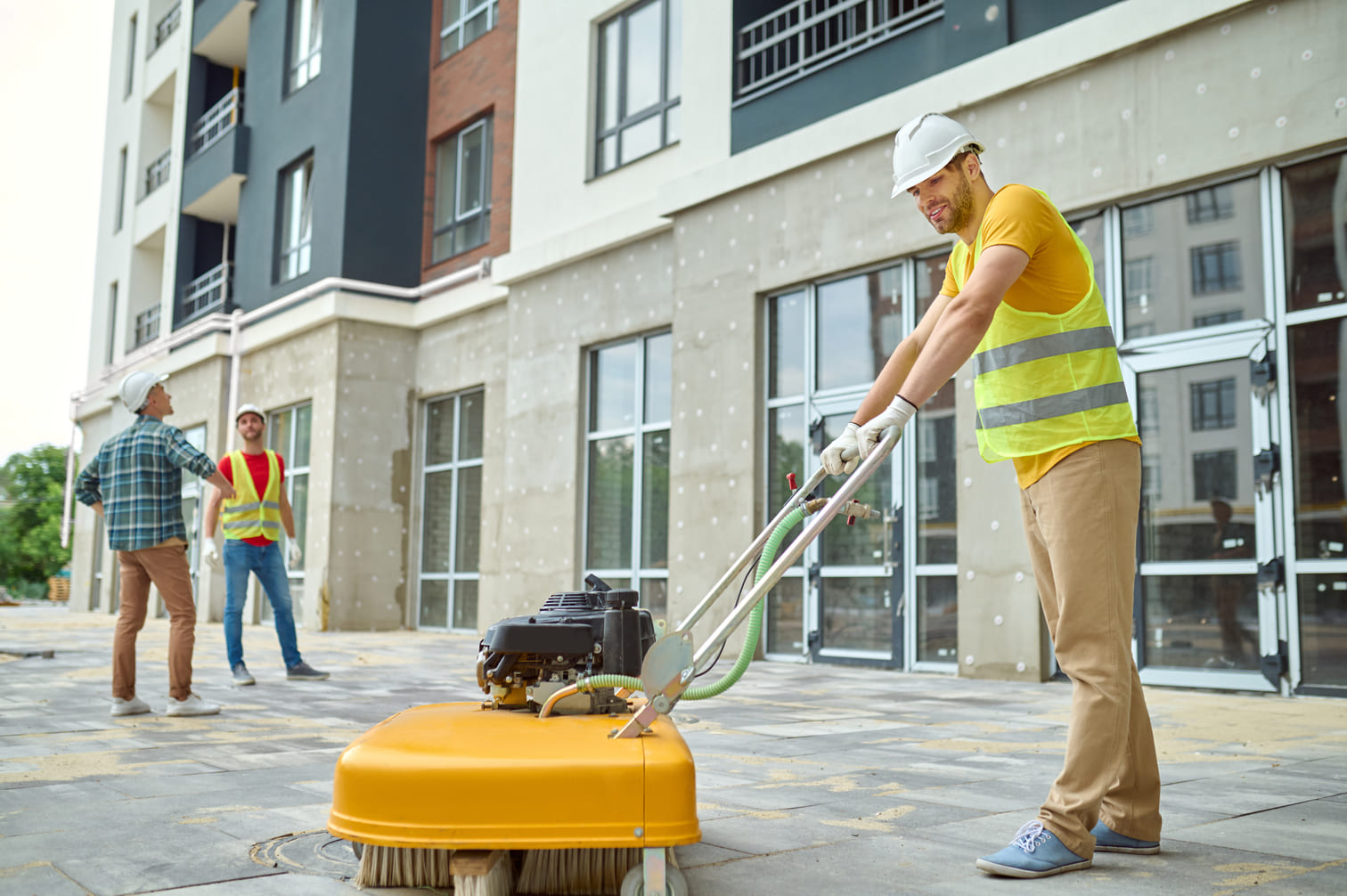 Arbeiter reinigt Baustelle und zwei Männer in der Nähe des Hauses.